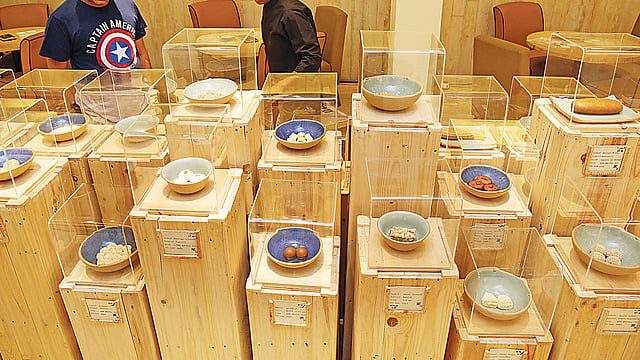 কাচের বাক্সে ভিন্ন ভিন্ন পাত্রে মিষ্টির নমুনা সাজানো রয়েছে।  ছবি: প্রথম আলো