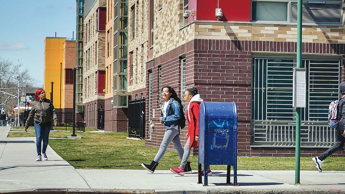 ব্রুকলিনের ইস্ট নিউইয়র্কের স্ট্যানলি কমন্সের কুখ্যাত ‘মৃত্যুর চৌমাথা’য় চলমান আবাসন প্রকল্পের পাশ দিয়ে হেঁটে যাচ্ছে শিক্ষার্থীরা। এখন পর্যন্ত নিরুদ্বেগভাবেই তারা চলাচল করতে পারছে। ছবি নিউইয়র্ক টাইমস–এর সৌজন্যে