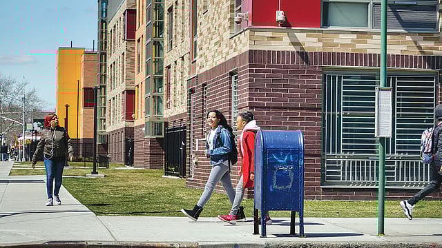 ব্রুকলিনের ইস্ট নিউইয়র্কের স্ট্যানলি কমন্সের কুখ্যাত ‘মৃত্যুর চৌমাথা’য় চলমান আবাসন প্রকল্পের পাশ দিয়ে হেঁটে যাচ্ছে শিক্ষার্থীরা। এখন পর্যন্ত নিরুদ্বেগভাবেই তারা চলাচল করতে পারছে। ছবি নিউইয়র্ক টাইমস–এর সৌজন্যে