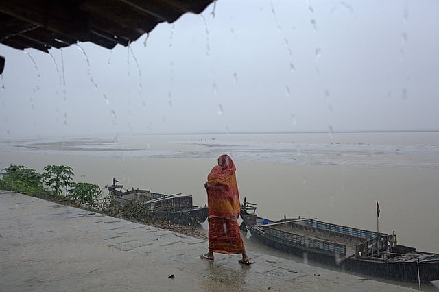 বৃষ্টির মধ্যে সন্তানকে আঁচলে ঢেকে রেখেছেন মা। রাজশাহী। ছবি: সুমন ইউসুফ
