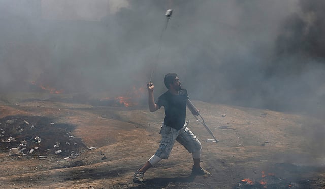ইসরায়েলি সেনাদের দিকে পাথর ছুড়ছেন একজন। ছবি: রয়টার্স