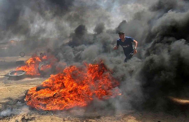 ইসরায়েলি সেনাবাহিনীর সঙ্গে সংঘর্ষের সময় প্রাণ বাঁচানোর চেষ্টা এক ফিলিস্তিনি তরুণের। গাজা, ১৪ মে। ছবি: এএফপি