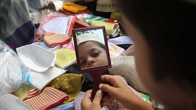 টুপিটা হতে হবে তার মনের মতো। জুমার নামাজ শেষে বাবার সঙ্গে টুপি কিনতে এসেছে সে। বায়তুল মোকাররম মসজিদ এলাকা, ঢাকা, ১৮ মে। ছবি: আবদুস সালাম