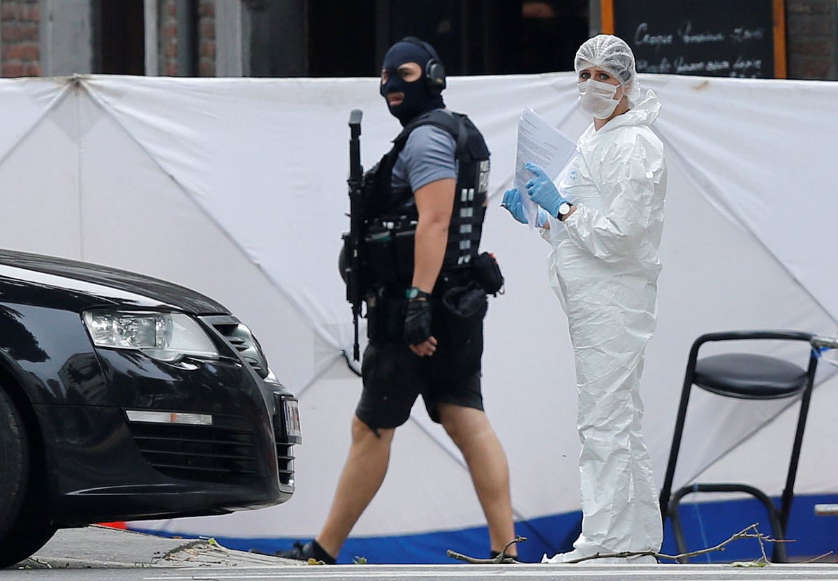 মুখোশ পড়া একজন পুলিশ সদস্য ও একজন ফরেনসিক বিশেষজ্ঞ ঘটনাস্থল থেকে আলামত সংগ্রহ করছেন। লি গে, বেলজিয়াম, ২৯ মে। ছবি: রয়টার্স