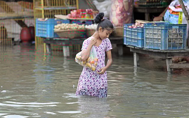 বৃষ্টি, জলাবদ্ধতা—তাতে কী। খেতে তো হবে। তাই বাধ্য হয়ে বাজারে আসতে হয়েছে এই শিশুকে।  আগ্রাবাদ সিডিএ এলাকা, চট্টগ্রাম, ১১ জুন। ছবি: জুয়েল শীল