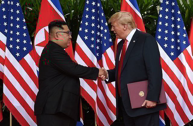 গুরুত্বপূর্ণ নথি সই শেষে করমর্দন করছেন কিম জং উন ও  ডোনাল্ড ট্রাম্প। ছবি: রয়টার্স