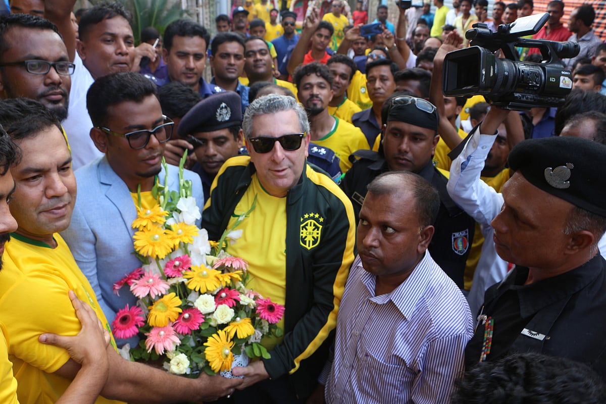 ব্রাজিলের রাষ্ট্রদূত জোয়াও তাবাজারা ডি অলিভেরিয়া জুনিয়রকে ফুল দিয়ে শুভেচ্ছা জানান বাড়ির মালিক জয়নাল আবেদিন (বাঁয়ে)। ফতুল্লা, নারায়ণগঞ্জ, ২২ জুন। ছবি: দিনার মাহমুদ