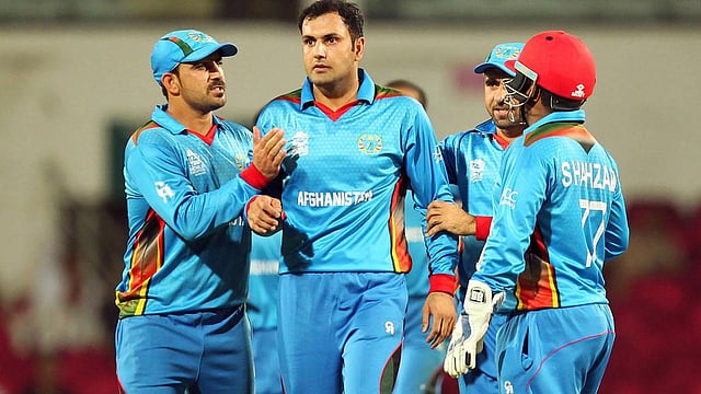 সাদা পোশাকে খেলতে নামার অনেক আগেই রঙিন পোশাকে ক্রিকেট বিশ্বে চমক দেখিয়েছে আফগানিস্তান। ছবি: এএফপি
