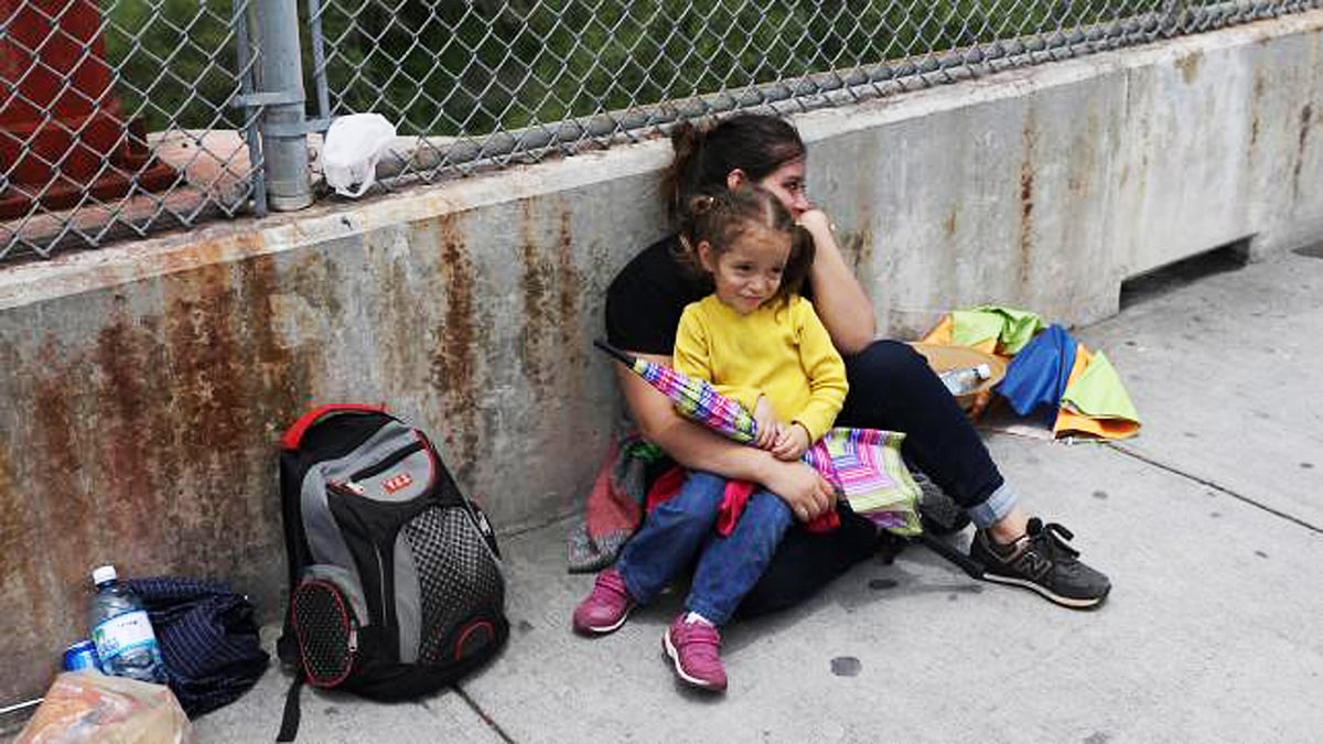 যুক্তরাষ্ট্রে প্রবেশে বাধা পাওয়ার পর টেক্সাসের ব্রাউন্সভিল-মাটামোরোস ইন্টারন্যাশনাল ব্রিজের পাশে অপেক্ষমাণ এক হন্ডুরান মা ও তাঁর তিন বছর বয়সী মেয়ে। ছবিটি ২৪ জুন তোলা। রয়টার্স/লরেন এলিয়ট
