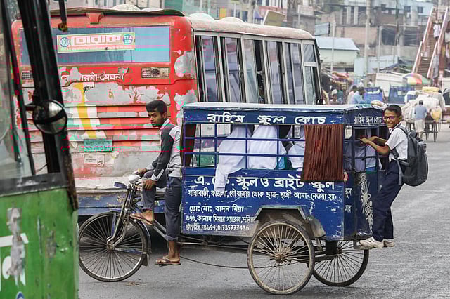 সন্তানদের স্কুল থেকে বাসায় আনতে অভিভাবকেরা নিশ্চিন্তে ভরসা রাখেন ছাত্রছাত্রীদের আনা-নেওয়ার কাজে থাকা স্কুল কোচের চালকদের ওপর। কিন্তু তাঁদের সচেতনতার যথেষ্ট অভাবও দেখা যায়। মহাসড়কে উল্টো পথ দিয়ে চলছে এ স্কুল কোচ, জায়গা না থাকায় পেছনে ঝুলে যাচ্ছে এক ছাত্র। দনিয়া, ঢাকা, ২৬ জুলাই। ছবি: দীপু মালাকার
