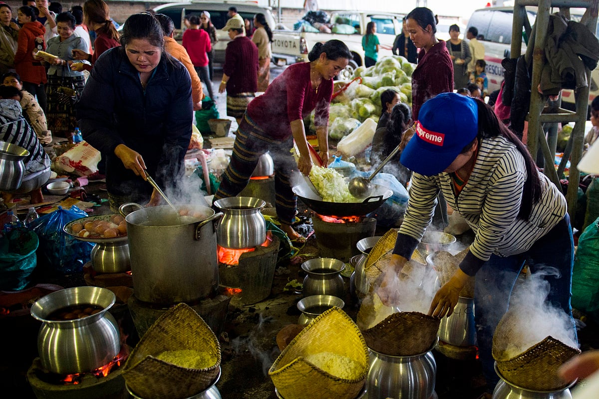 দুর্গত মানুষের জন্য রান্না করছেন স্বেচ্ছাসেবীরা। বাঁধ ধসে বন্যার ঘটনায় এখন পর্যন্ত নিখোঁজ ১৩১ জন। ২৫ জুলাই। ছবি: এএফপি