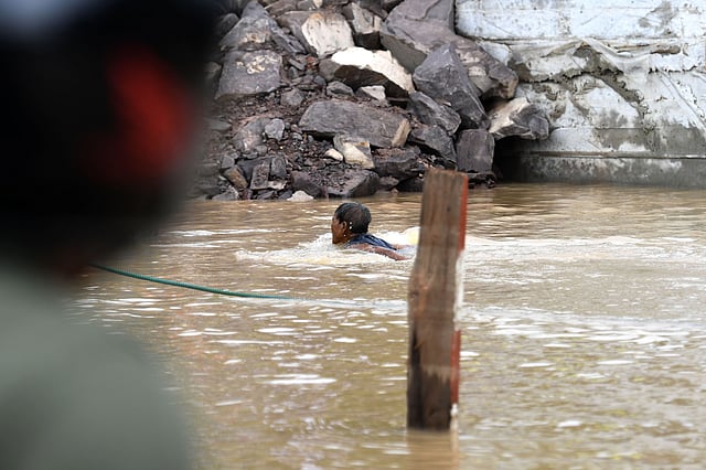 বন্যায় ফুঁসে উঠেছে জে খং নদী। সেখানে সাঁতার কাটছেন এক ব্যক্তি। ২৫ জুলাই। ছবি: এএফপি