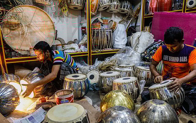 বাদ্যযন্ত্রের খুচরা ও পাইকারি বিক্রির দোকানে তবলা বানানোর কাজ করছেন এক কর্মী। পিতল, কাঠ আর চামড়া দিয়ে তৈরি এক জোড়া তবলা খুচরা বাজারে ৩ হাজার ৫০০ টাকা থেকে ৮ হাজার টাকা পর্যন্ত কিনতে পাওয়া যায়। শাঁখারী বাজার, ২৬ জুলাই। ছবি: দীপু মালাকার