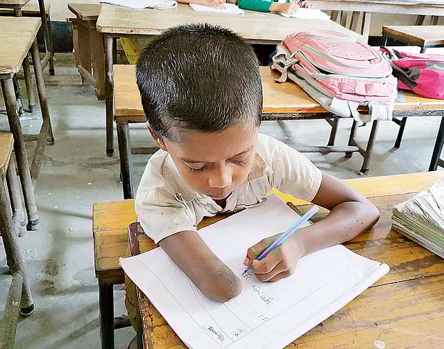 লিখছে শিশু মুজাহিদ হোসেন। শনিবার  তোলা ছবি।  প্রথম আলো