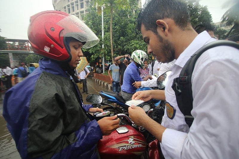 শাহবাগ মোড়ে এক মোটরসাইকেল চালকের লাইসেন্স যাচাই করছে একদল শিক্ষার্থী। ঢাকা, ২ আগস্ট। ছবি: আবদুস সালাম