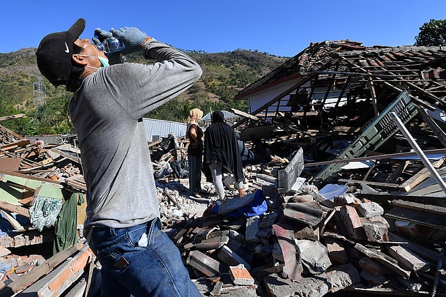ধ্বংসস্তূপ পরিষ্কার করতে করতে ক্লান্ত হয়ে পানি পান করছেন এক ব্যক্তি। মেনগালা, বাংসাল, ইন্দোনেশিয়া, ৮ আগস্ট। ছবি: এএফপি