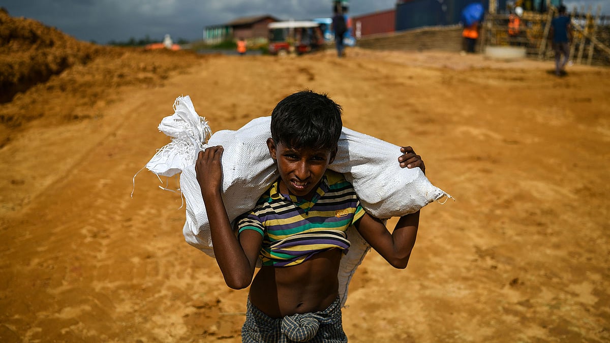বস্তা নিয়ে হাঁটছে এক বালক। গত মঙ্গলবার উখিয়ার কুতুপালং আশ্রয়শিবিরে।  এএফপি