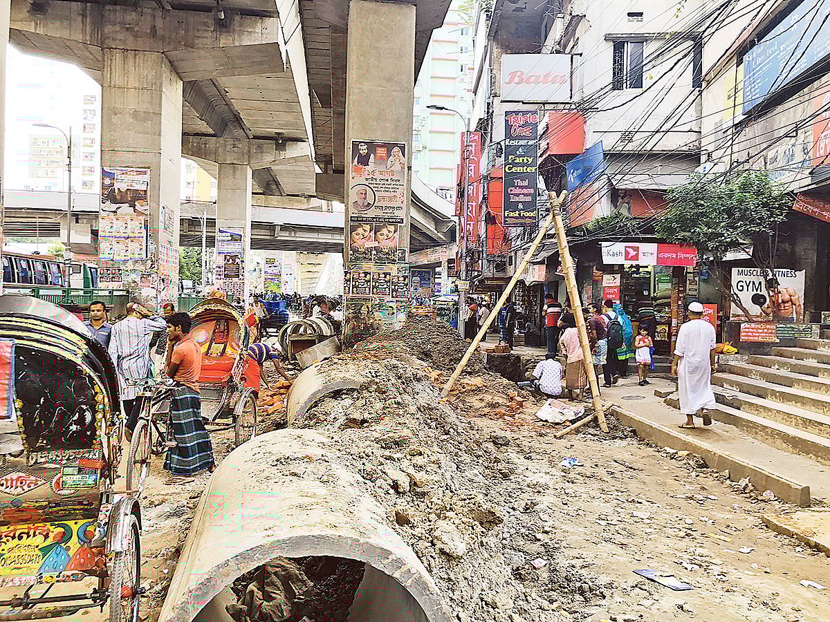 মগবাজার–মৌচাক সড়কের দুই পাশে খুঁড়ে পাইপ বসানো হচ্ছে। গতকাল দুপুরে মগবাজার মোড়ে।