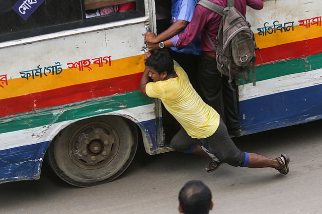 ঝুঁকি নিয়ে চলন্ত বাসে উঠতে গিয়ে পড়ে যান এই যাত্রী। কারওয়ান বাজার, ঢাকা। ছবি: সাইফুল ইসলাম