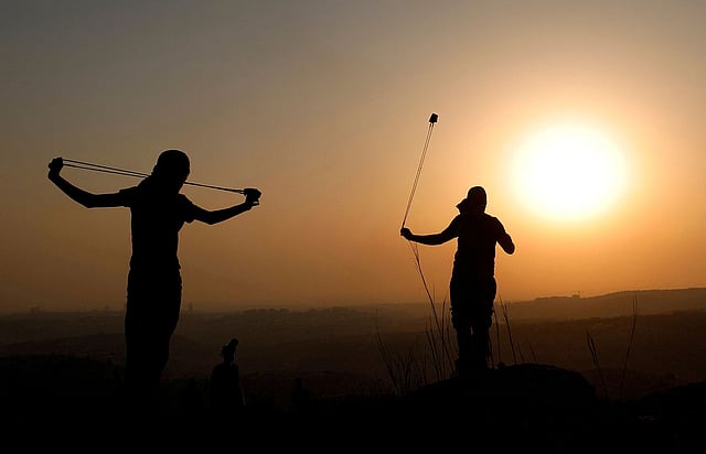 ইসরায়েলি সেনাদের লক্ষ্য করে পাথর ছুড়ছেন ফিলিস্তিনি বিক্ষোভকারীরা। ইহুদি বসতি স্থাপনে জমি দখলের প্রতিবাদে এই পাথব ছোড়া। রাস কারকার, রামাল্লা, অধিকৃত পশ্চিম তীর, ৪ সেপ্টেম্বর। ছবি: রয়টার্স