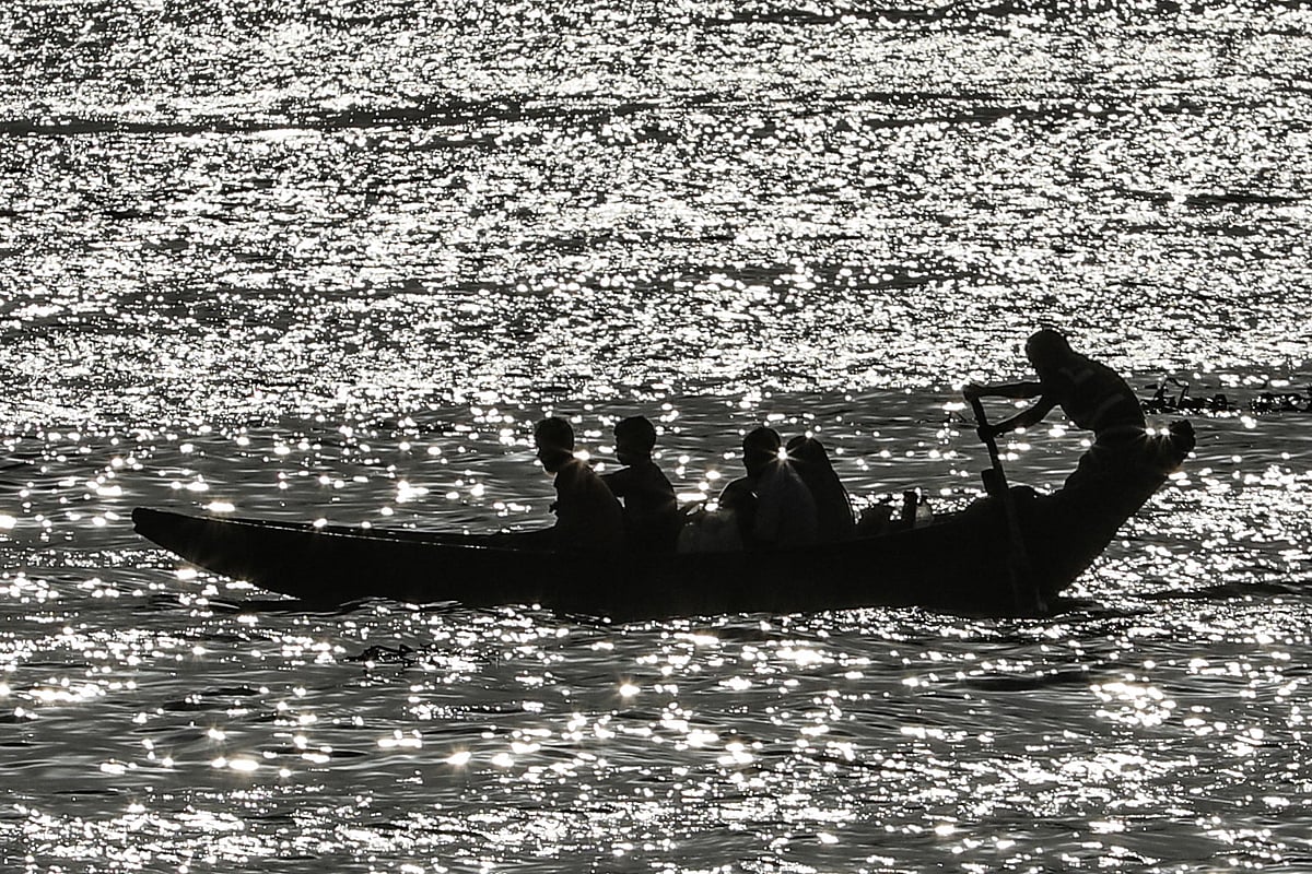পড়ন্ত বিকেলে রৌদ্রোজ্জ্বল ঢেউয়ের তালে যাত্রীসমেত মাঝি।