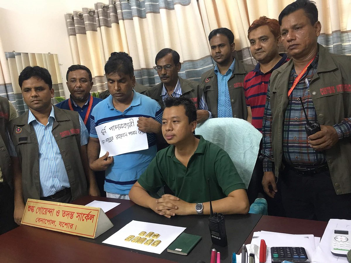 আটক যাত্রী মাসুদুর রহমান (বুকে সাদা কাগজ লাগানো)। ছবি: মাসুদ আলম