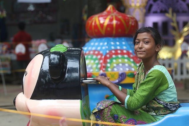 খেলনা ট্রেনে চড়েছে এক ছিন্নমূল শিশু।