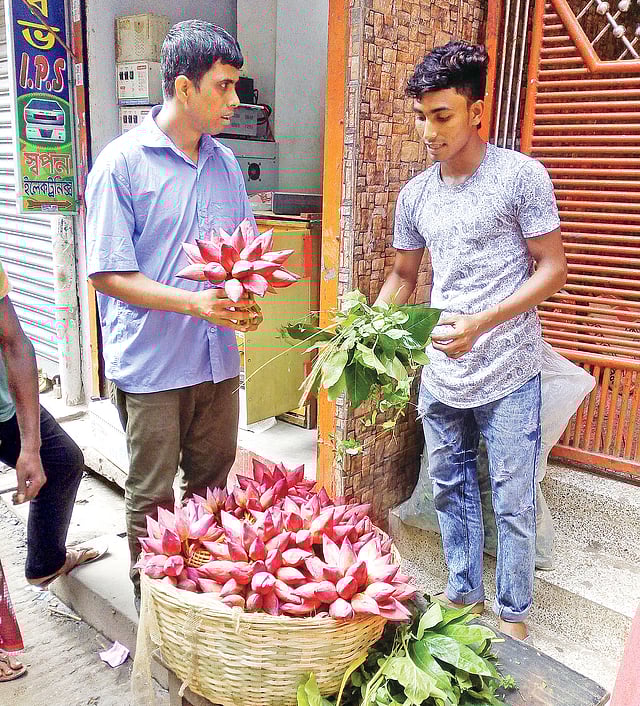 পূজার জন্য পদ্ম ফুল কিনছেন এক ভক্ত। গতকাল শাঁখারীবাজারে।  ছবি: জয়দেব সরকার