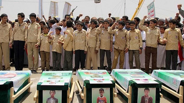 ইয়েমেনের সাদায় এ বছরের আগস্ট মাসে স্কুলবাসের ওপর সৌদি আরব নেতৃত্বাধীন জোট হামলা চালালে বহু শিশু নিহত হয়। নিহত শিশুদের গণদাফন অনুষ্ঠানে অংশ নেয় অন্য শিশুরা। ছবি: এএফপি