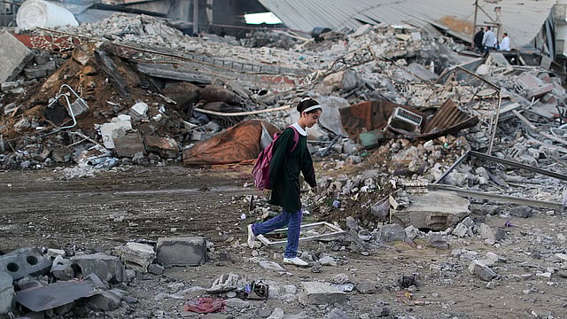 ইসরায়েলের বিমান হামলায় ধংসস্তূপে পরিণত হয়েছে গাজার এই এলাকা। এর মধ্য দিয়ে স্কুলে যাচ্ছে ফিলিস্তিনের এই খুদে শিক্ষার্থী। গাজা সিটি, ফিলিস্তিন, ২৭ অক্টোবর। ছবি: রয়টার্স