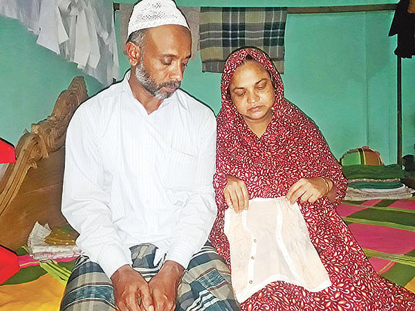মৌলভীবাজারের বড়লেখায় গত রোববার পরিবহনশ্রমিকদের আটকানো অ্যাম্বুলেন্সের ভেতর মারা যায় সাত দিন বয়সী শিশুকন্যা খাদেজা বেগম। শিশুটির বাড়ি উপজেলার সদর ইউনিয়নের অজমীর গ্রামে। মেয়ের জামা হাতে নিয়ে নির্বাক তাঁরা। গতকাল বিকেলে। ছবি: প্রথম আলো