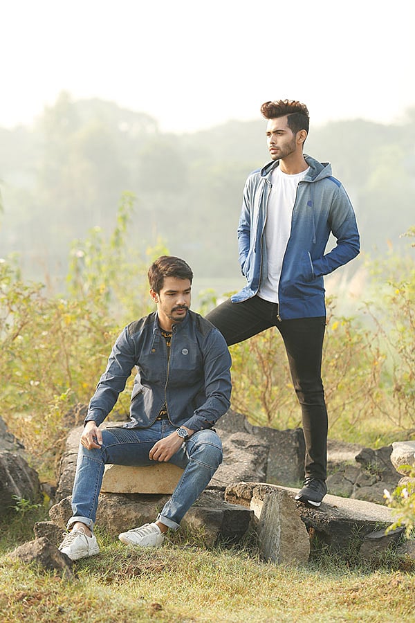 কুল ডাই (একই পোশাকে এক রঙের দুই শেড) করা হুডির কাপড়ে ব্যবহার করা হয়েছে নিট ডেনিম। পাশের খুদে ডটপ্রিন্টের এই জ্যাকেট দেখতে শার্টের মতো। ব্যান্ড কলারের জ্যাকেটের সামনের চেইন এনেছে বৈচিত্র্য।  জ্যাকেট: ব্যাঙ, মডেল নীল ও মুদ্দাসির। ছবি: সুমন ইউসুফ