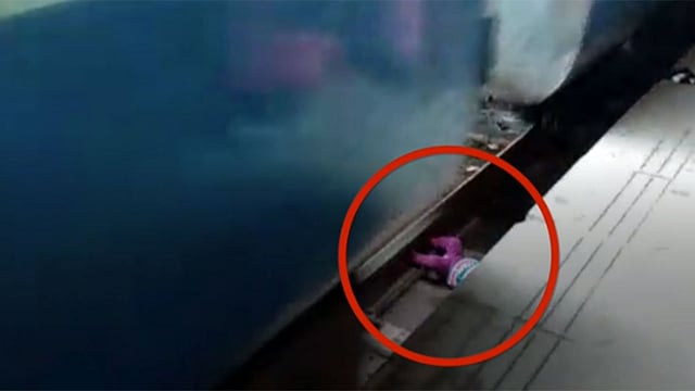 রেললাইনের ফাঁকে পড়ে আছে এক বছরের শিশুটি। ছবিটি বিবিসির ভিডিও থেকে নেওয়া