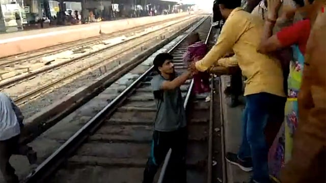 ট্রেন চলে যাওয়ার পর রেললাইন থেকে শিশুটিকে তুলে আনেন এক যুবক। ছবিটি বিবিসির ভিডিও থেকে নেওয়া