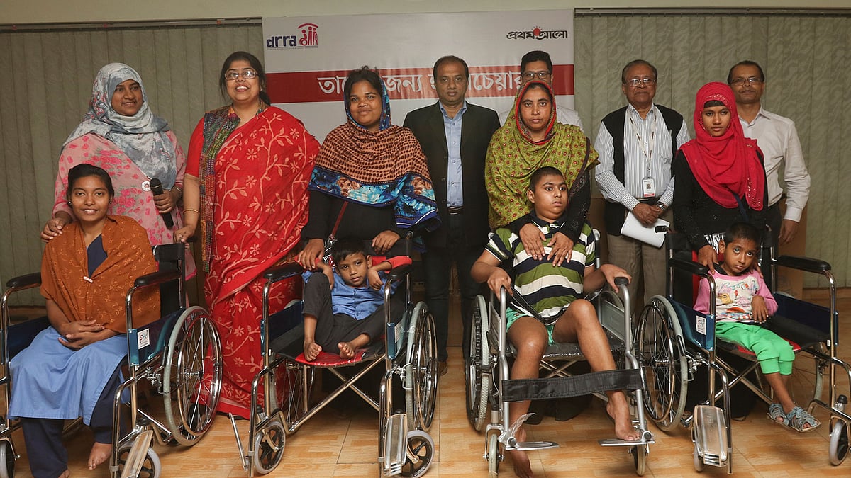 হুইলচেয়ার পাওয়া চার শিশুর সঙ্গে তাদের স্বজন ও অতিথিরা। ছবি: প্রথম আলো