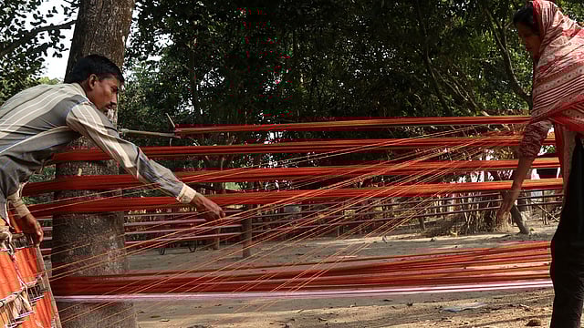 তানা কাড়াচ্ছেন (সুতা টানা) রঞ্জু প্রামাণিক ও বিউটি বেগম দম্পতি। ছবি: সোয়েল রানা