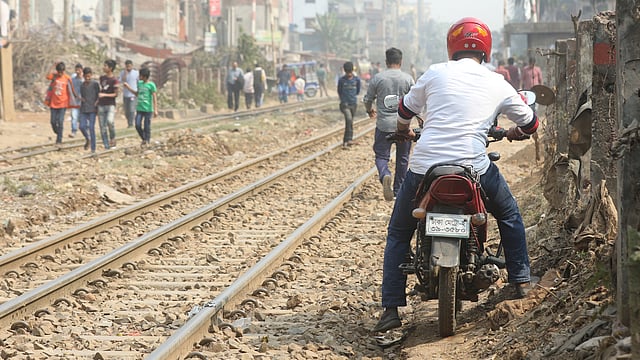 রেললাইনের পাশের এবড়োখেবড়ো পথ দিয়ে চলছে মোটরসাইকেল। এদিক দিয়ে যান চলাচল সম্পূর্ণ নিষিদ্ধ হওয়া সত্ত্বেও অনেকে ঝুঁকি নিচ্ছেন।