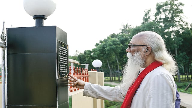 নেত্রকোণার মালিনীতে কবিতাকুঞ্জের প্রবেশপথের ফলকে নিজের লেখা ‘আমন্ত্রণ’ কবিতাটির সামনে কবি। ছবি: প্রথম আলো