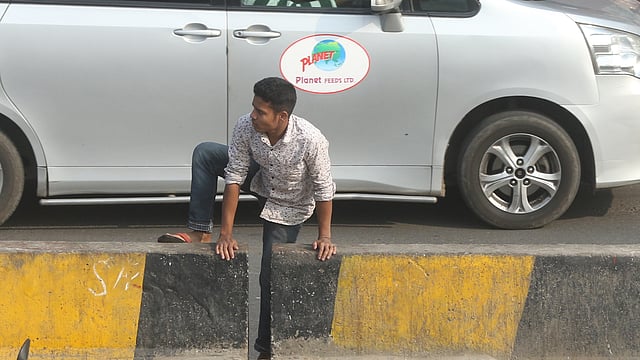 মহাখালীর সড়ক বিভাজক ডিঙিয়ে সড়ক পার হচ্ছেন এক পথচারী।