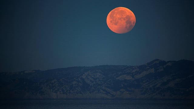 ফ্রান্সের পাহাড়ি এলাকা থেকে দেখা লাল ‘নেকড়ে চাঁদ’। ছবি: রয়টার্স