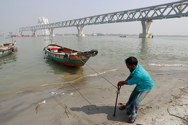 পদ্মা নদীতে ট্রলার চালিয়ে চলে আনোয়ার হাওলাদারের জীবন। প্রমত্তা নদীর ওপর গড়ে উঠছে স্বপ্নের এই সেতু। পেশা নিয়ে শঙ্কা থাকলেও আনোয়ার মনেপ্রাণে চাইছেন, যেন শেষ হয় সেতুর নির্মাণকাজ। ছবি : শুভ্র কান্তি দাশ