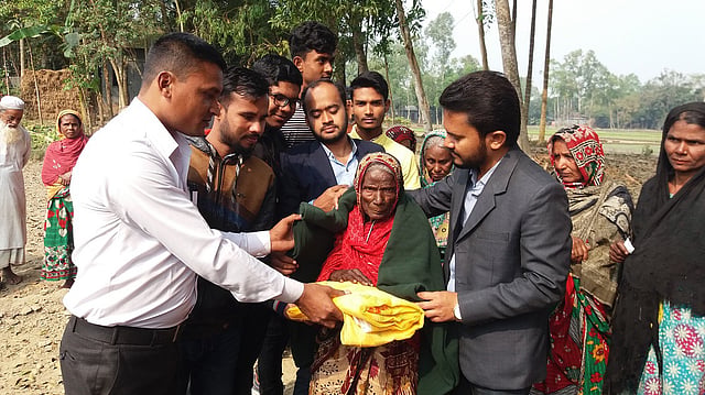 শীতার্ত বিধবা নারীর গায়ে কম্বল জড়িয়ে দিচ্ছেন বন্ধুসভার সদস্যরা। পূর্ব রূপারপাড়া গ্রাম, শ্রীবরদী, শেরপুর, বৃহস্পতিবার। ছবি: দেবাশীষ সাহা রায়