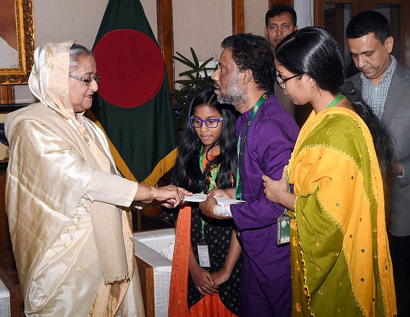 আকবরের হাতে সঞ্চয়পত্র ও চেক তুলে দিচ্ছেন প্রধানমন্ত্রী শেখ হাসিনা। ছবি: ফোকাস বাংলা