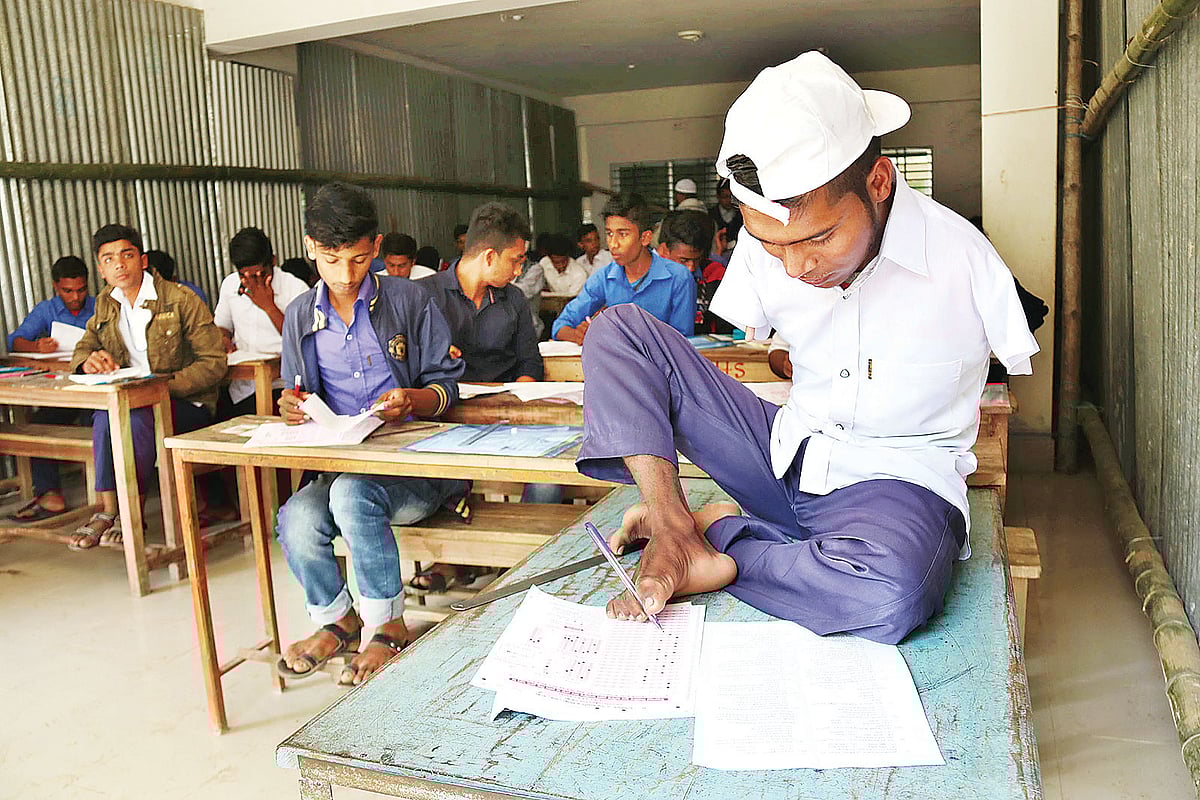 পা দিয়ে লিখে এসএসসি পরীক্ষা দিচ্ছে জসীম মাতুব্বর। গতকাল ফরিদপুরের নগরকান্দার এম এ শাকুর মহিলা কলেজ কেন্দ্র। ছবি: প্রথম আলো