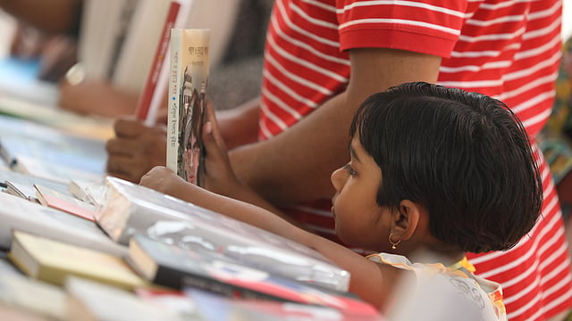 একটি স্টলে সাজানো অনেক বই থেকে নিজের বইটি খুঁজে নিচ্ছে একজন। সোহরাওয়ার্দী উদ্যান, ঢাকা, ৮ ফেব্রুয়ারি। ছবি: আবদুস সালাম