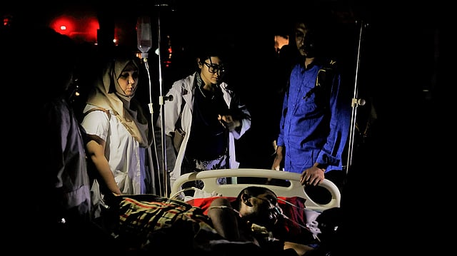 আগুন লাগার পরে হাসপাতালের সামনের মাঠে নেওয়া এক রোগীকে দেখছেন চিকিৎসকেরা। ঢাকা, ১৪ ফেব্রুয়ারি। ছবি: খালেদ সরকার