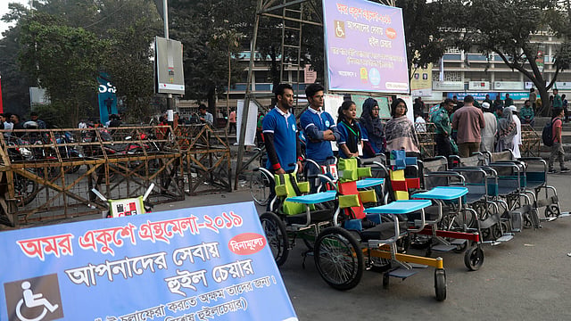 বেসরকারি সংগঠন সুইচ বাংলাদেশ ফাউন্ডেশন চার বছর ধরে বইমেলার প্রবেশমুখে বিনা মূল্যে হুইলচেয়ার সেবা দিয়ে যাচ্ছে। ছবি: প্রথম আলো