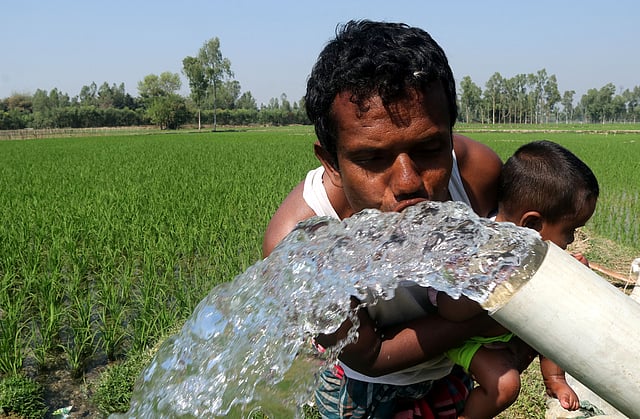 খেতে সেচ দেওয়ার সময় শ্যালো মেশিনের পানিতে গলা ভিজিয়ে নিচ্ছেন এক ব্যক্তি। সোনাকানিয়া, শাজাহানপুর, বগুড়া, ২৪ ফেব্রুয়ারি। ছবি: সোয়েল রানা