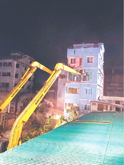 হেলে পড়া ভবনটি এক্সকাভেটর দিয়ে ভাঙা হচ্ছে। গতকাল সন্ধ্যায় কামরাঙ্গীরচরে। প্রথম আলো