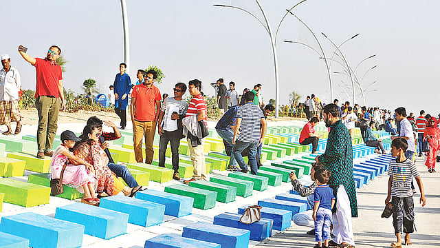 সৈকতে নির্মিত রঙিন বসার স্থানে দর্শনার্থীরা। গতকাল বিকেলে।  প্রথম আলো
